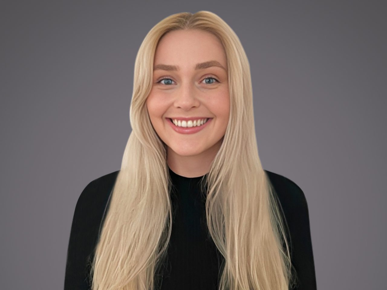 A person with long, straight blonde hair and blue eyes, wearing a black top, smiling at the camera against a plain grey background.