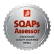 Medaglia argentata con bordo dentellato; logo rosso in alto; testo rosso: “SOAPS Assessor”; in basso, “Stakeholder Quality Assurance Panels”.