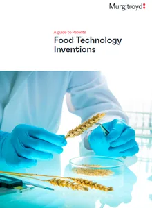 Scientist in blue gloves handling wheat stalks above a glass petri dish on a lab bench.