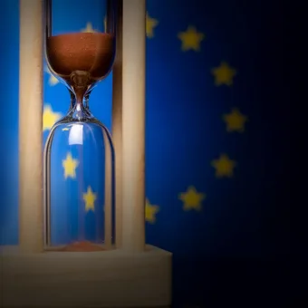 An hourglass with brown sand against a European Union flag background.