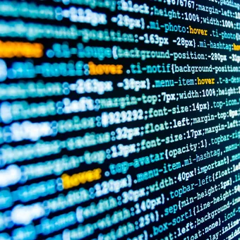 Close-up of colorful programming code on a screen, with lines of HTML/CSS code highlighted in yellow and blue.