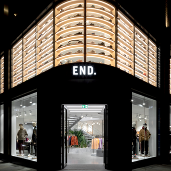 A person in a blue blazer and light blue shirt smiles at the camera against a neutral grey gradient background.