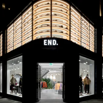 A person in a blue blazer and light blue shirt smiles at the camera against a neutral grey gradient background.