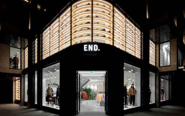 Store with illuminated shoe displays on the upper level, mannequins in the windows, and a sign reading "END." at the entrance, set at night.