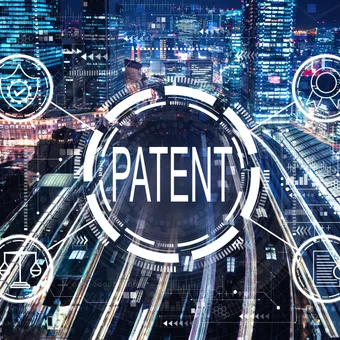 Cityscape at night with digital overlay of patent icons and futuristic graphics surrounding the word "PATENT" in the centre.