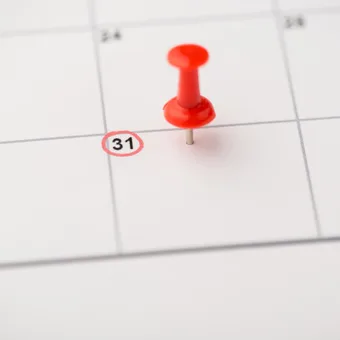 A red pushpin on a calendar marking the date of the 31st, with the number circled in red.
