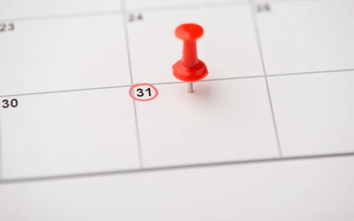A red pushpin on a calendar marking the date of the 31st, with the number circled in red.