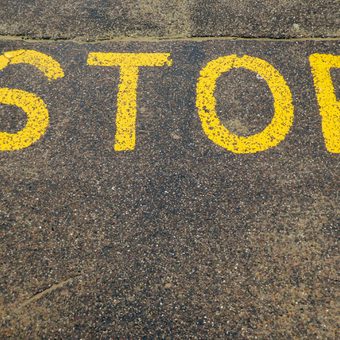 Yellow "STOP" sign painted on rough pavement surface.