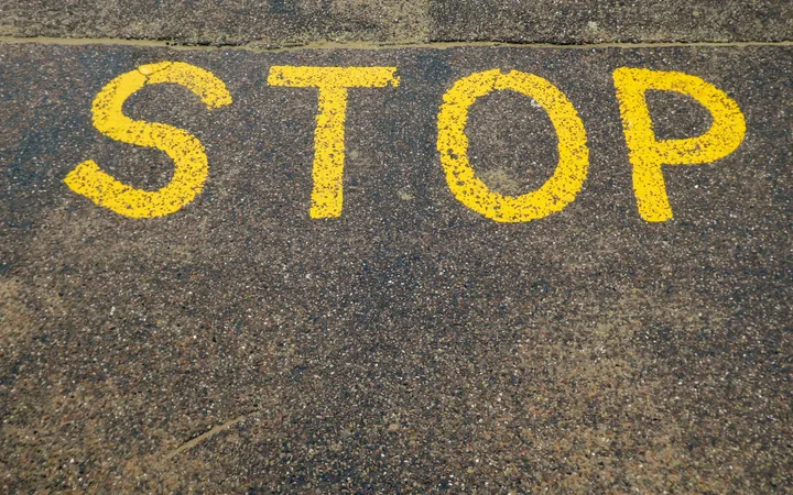 Yellow "STOP" sign painted on rough pavement surface.
