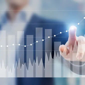 A person in business attire interacts with a virtual financial chart displaying bar graphs and rising line graphs, suggesting growth and data analysis.