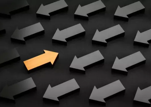A yellow arrow points in a different direction among many black arrows all facing the same way on a dark background.