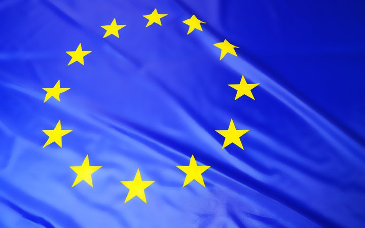 European Union flag with yellow stars on a crinkled blue background.