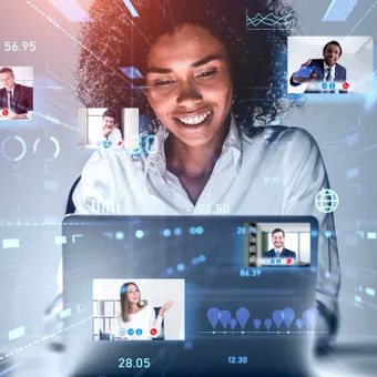 A woman interacts with a virtual video conference interface featuring multiple small video call screens of diverse colleagues behind digital data overlays.