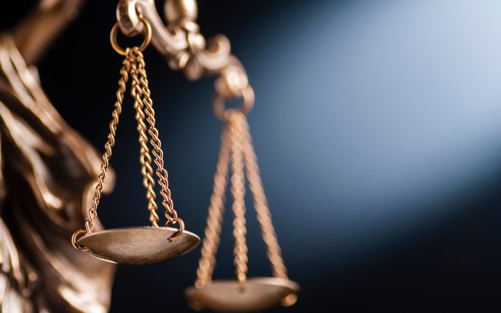 Close-up of a brass balance scale with chains, set against a dark background, symbolising justice and fairness.