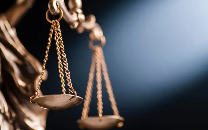 Close-up of a brass balance scale with chains, set against a dark background, symbolising justice and fairness.