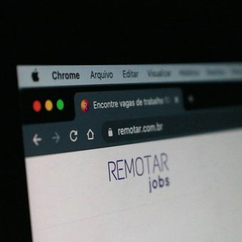 Close-up of a computer screen displaying a website with the text "REMOTE jobs" and browser tabs, against a dark background.