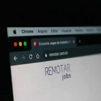 Close-up of a computer screen displaying a website with the text "REMOTE jobs" and browser tabs, against a dark background.