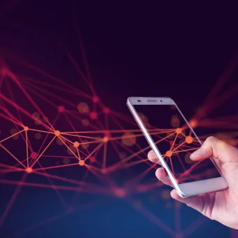 A hand holding a smartphone with digital network lines and points emanating from the device against a dark background.