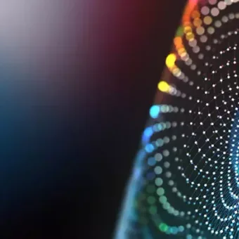 A colourful array of dots forming a spiral pattern against a dark background, creating a sense of motion and digital or technological theme.