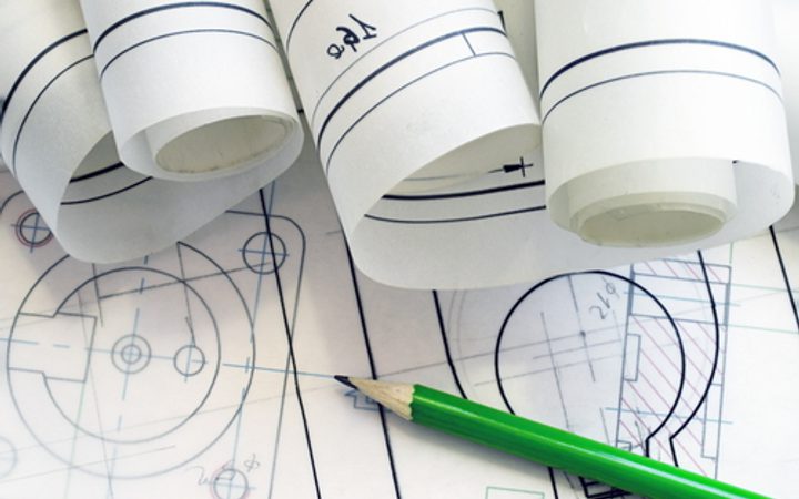 Technical drawings and blueprints with rolled-up plans, a green pen, and detailed sketches on blueprints.