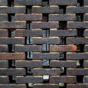 Mur en briques rouges et noires avec des espaces entre les briques, vue en gros plan.