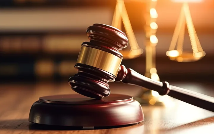 A judge's gavel resting on a sound block with a balanced scale in the background, symbolising justice and legal proceedings.