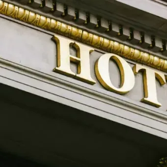 Close-up of a building façade with a gold-lettered sign reading "HOTEL" and ornate gold decorative elements.