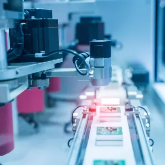 A robotic arm inspects printed circuit boards on an assembly line in a high-tech manufacturing environment.