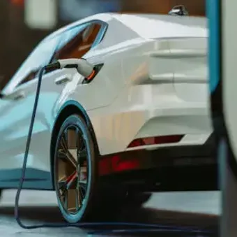 Head-and-shoulders portrait of an individual in a dark suit, white shirt and blue-striped tie, smiling slightly against a grey gradient background.
