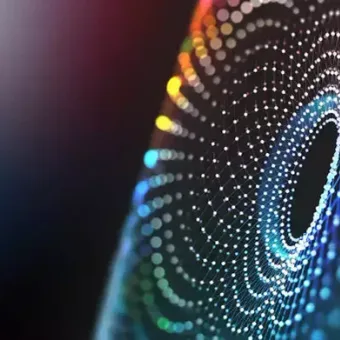 A digital abstract image with concentric circles of colorful dots forming a spiral pattern on a dark background.