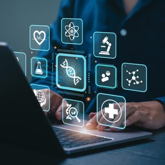 Person using a laptop with holographic health, science, and research icons floating above the keyboard.