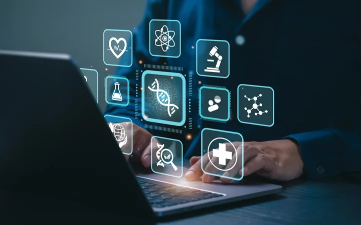 Person using a laptop with holographic health, science, and research icons floating above the keyboard.