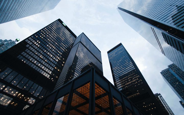 Low-angle view of tall modern glass skyscrapers against a cloudy sky.