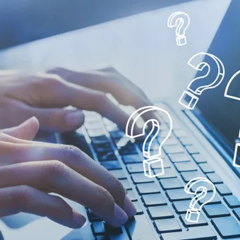 Hands typing on a laptop keyboard with white question marks floating above, suggesting curiosity or inquiry.