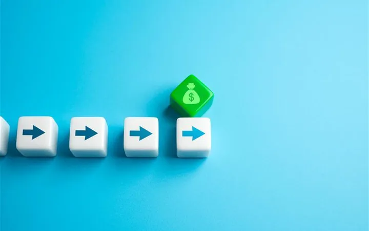 Five white dice with blue arrows pointing right, leading to a green die with a money bag and dollar sign, on a light blue background.