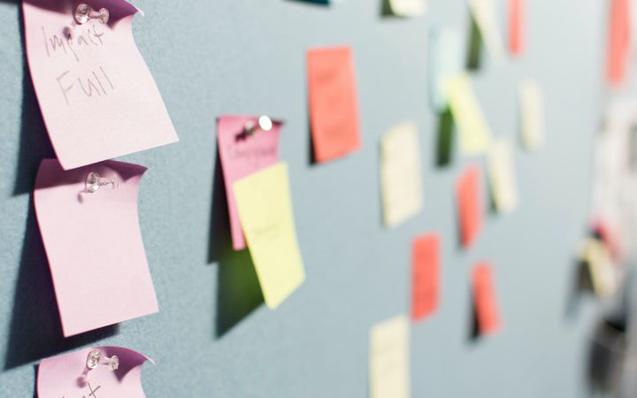 Colorful sticky notes attached to a gray board with push pins, some with handwritten words, arranged in a pattern with a focus on pink notes reading "Important" and "Full."