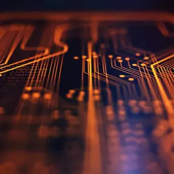 Close-up of glowing orange and yellow circuit pathways on a dark microchip or circuit board.