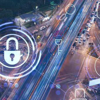 A city street view at night with digital security icons and graphics superimposed, illustrating cybersecurity technology overlay on urban infrastructure.