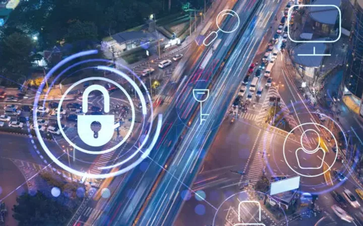 Aerial view of a city street at night with digital security icons overlaid, including a padlock, user profile, and Wi-Fi symbols.