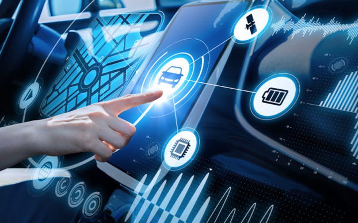 A person interacts with a digital interface inside a vehicle, displaying icons related to navigation, communication, and battery life over a high-tech dashboard.