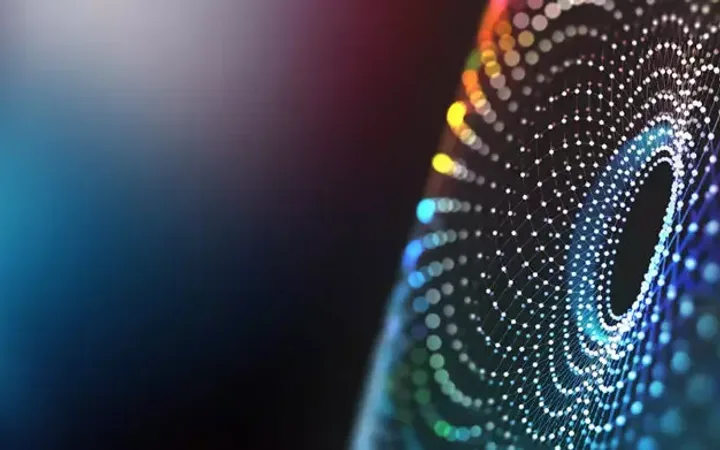 An abstract digital design with colourful glowing dots forming a concentric circular pattern against a dark background.