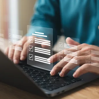 Person using a laptop with transparent digital checklists or forms floating above the keyboard.