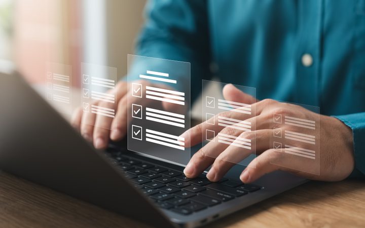 Person using a laptop with transparent digital checklists or forms floating above the keyboard.