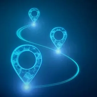 Portrait of a person with long wavy dark hair, wearing a blue knit sweater, smiling softly against a neutral gray background.