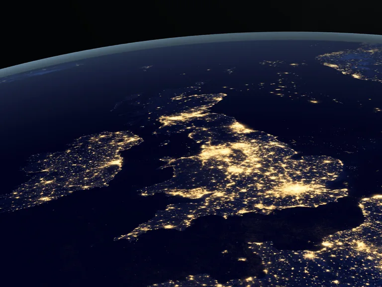 Curved view of Earth at night, Europe lit by city lights along the UK, France, Italy and the Mediterranean coast, with a dark space background.