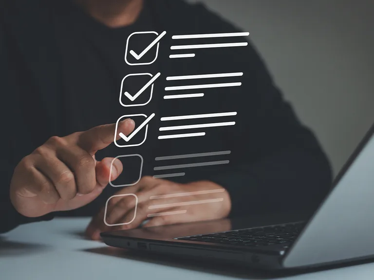 Persona che tocca una lista di controllo digitale con tre vasi e segni di spunta, con uno mentre tiene un laptop sul tavolo.