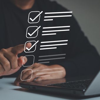 A person interacts with a digital checklist overlaid on a laptop, with three checked boxes and additional unmarked options.