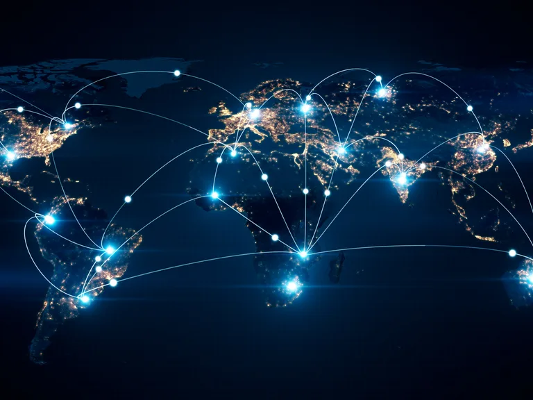 Night-time world map with illuminated golden continents and glowing blue network nodes linked by curved lines across the globe.