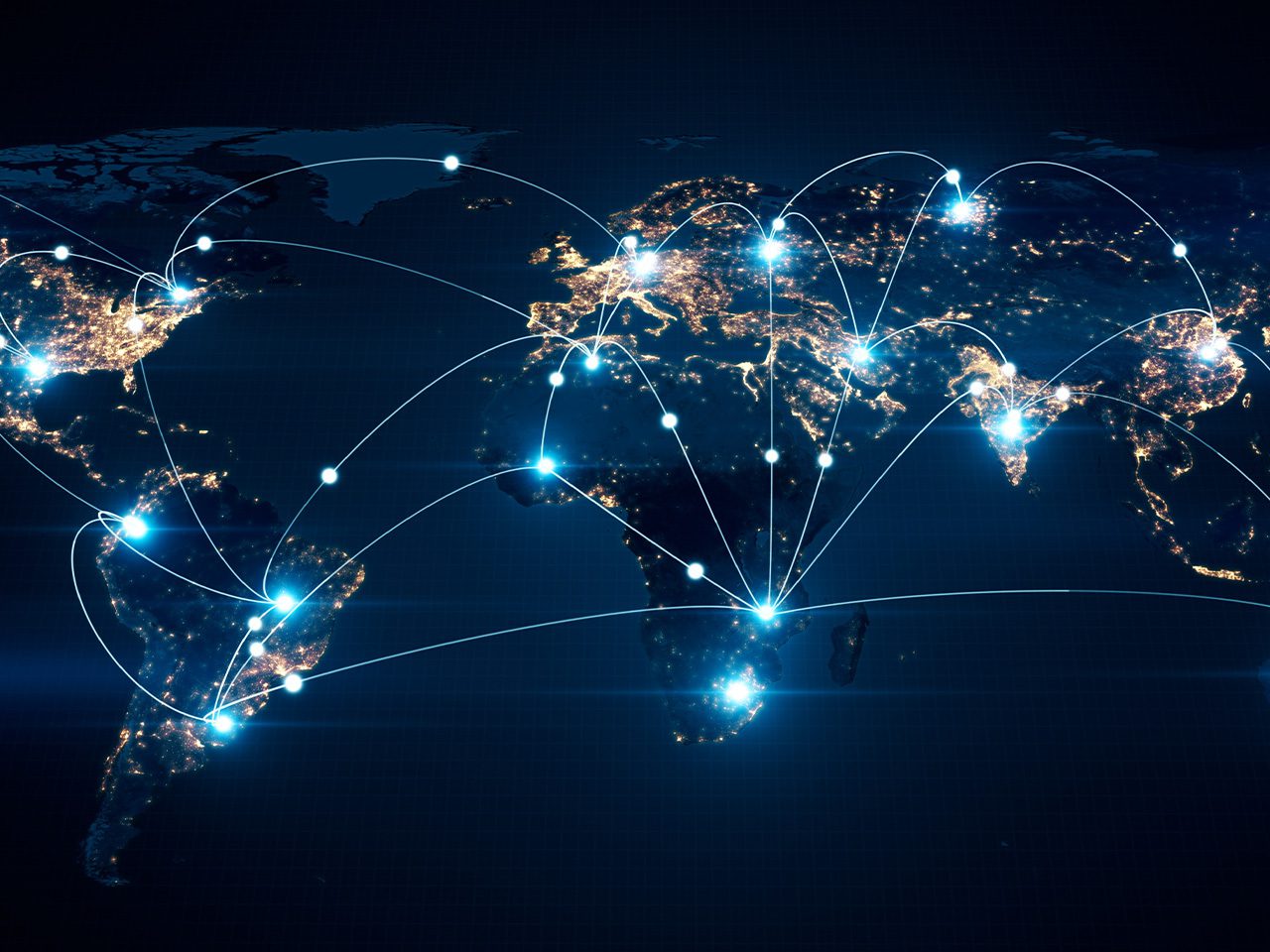 World map at night illustrating global connectivity with bright, glowing city lights and interconnected lines across continents.