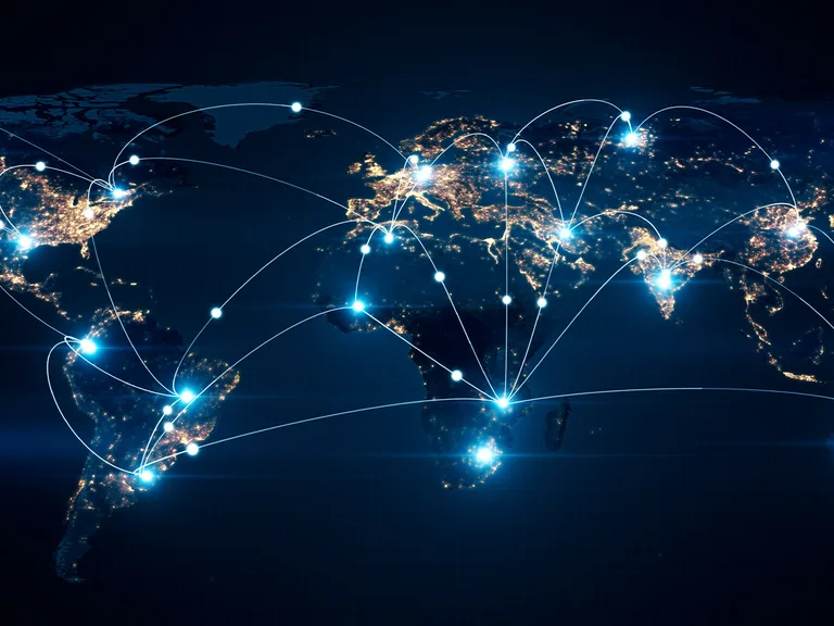 World map at night illustrating global connectivity with bright, glowing city lights and interconnected lines across continents.